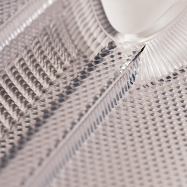 A precision-machined PMMA headlight lens prototype, featuring complex internal textures for optimal 